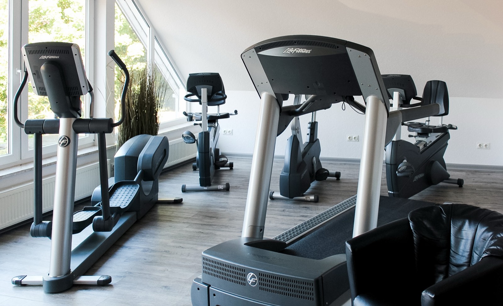 Fitnessraum im Hotel Ripken mit Laufband, Crosstrainer und Ergometern an der Fensterfront